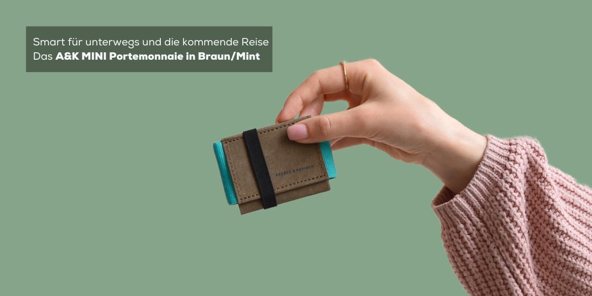 Ein A&K MINI Slim Wallet in Braun/Mint, gehalten von einer Frau mit einem rosafarbenen Pullover. Der Hintergrund ist einfarbig in Mint gehalten, was die frische und moderne Ästhetik des Produkts unterstreicht.